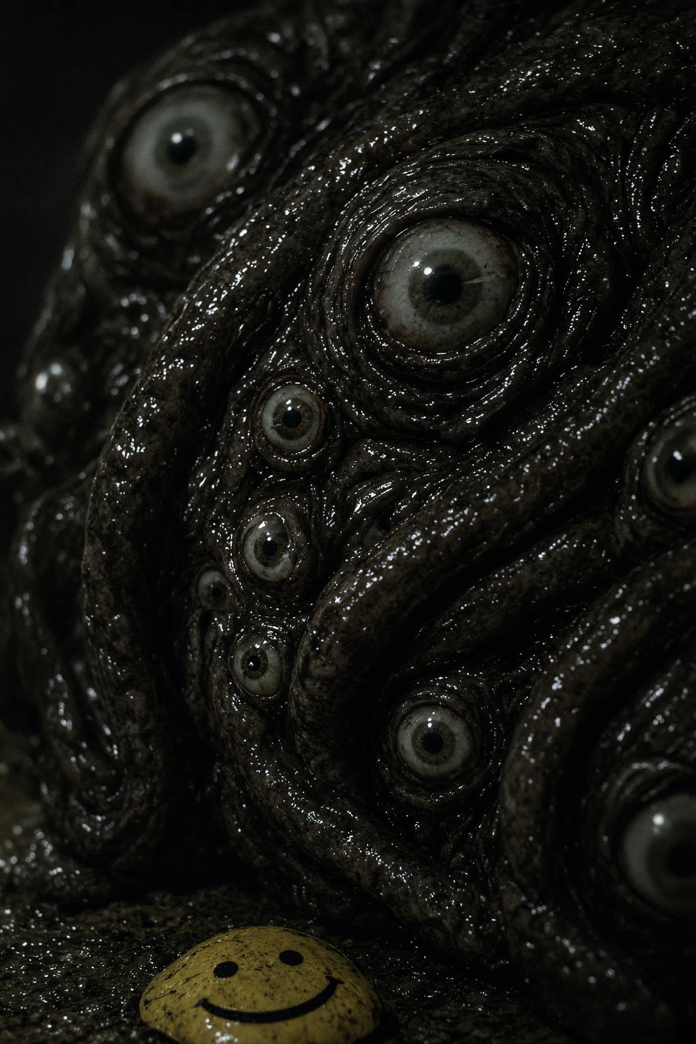 Extreme close photograph of wet dark coils covered in large open eyes, filling the whole frame.